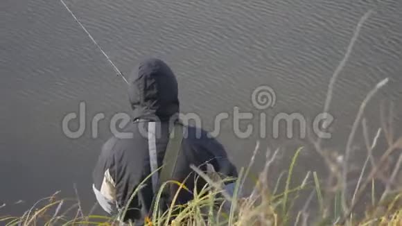 秋天在湖上迎风垂钓穿着梭子鱼旋转工作服的渔夫视频的预览图