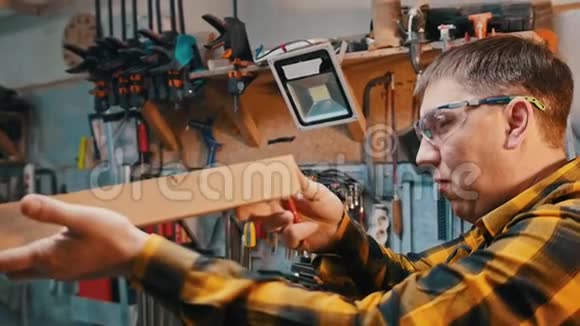 木工行业在车间工作一名戴防护眼镜的木工检查木制细节视频的预览图