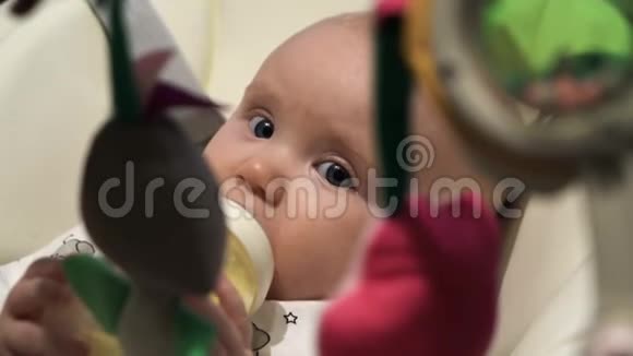 很漂亮的婴儿喝牛奶从瓶子里看镜头视频的预览图