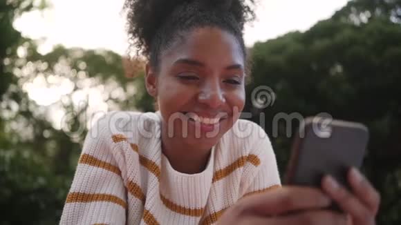 一位非洲年轻女性在户外使用智能手机的低角度视角视频的预览图