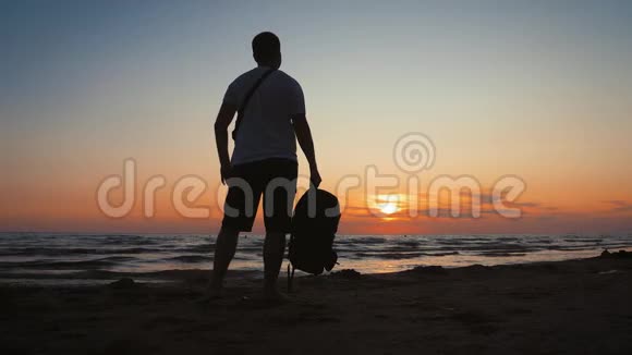 旅行人带背包的剪影在热带海滩享受日落沿着海岸旅行自由活跃视频的预览图