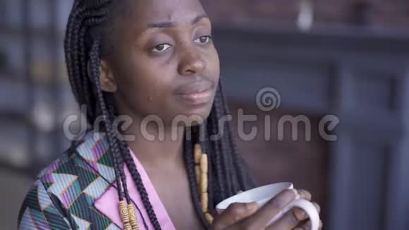 体贴的非裔美国女人带着一杯茶或咖啡看着远方有皮肤问题的女孩在家休息视频的预览图