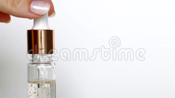 白色背景下从化妆品吸管中流出的滴金血清视频的预览图