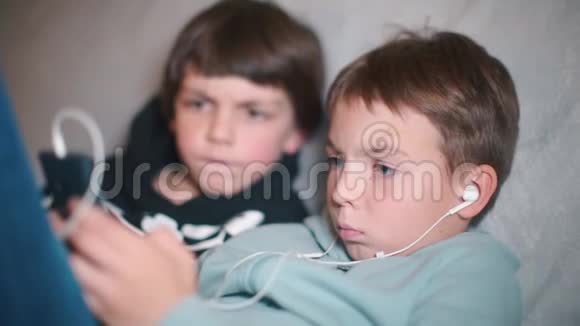 两个男孩坐在家里使用智能手机视频的预览图