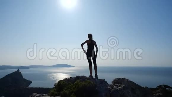 自信的年轻女子站在日出的山顶上一位女士在美丽的克里米亚山区徒步旅行的剪影视频的预览图
