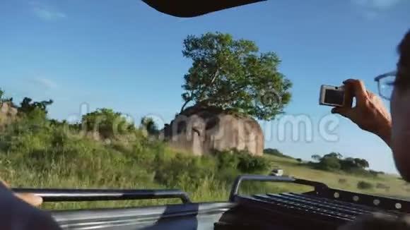 男子驾驶着野人吉普车在非洲平原的屋顶汽车上拍照视频的预览图
