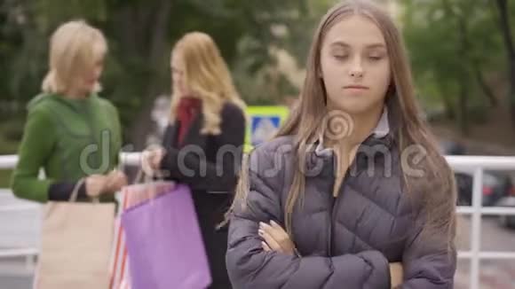 年轻悲伤的女人羡慕前景而她的两个美丽的金发女朋友站在街上展示她的前景视频的预览图