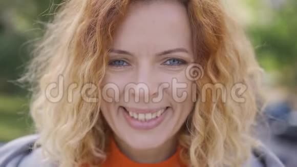 可爱的成熟的红头发的卷发的笑着开心地看着公园里的摄像机的特写视频的预览图