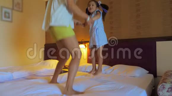 妈妈和女儿在酒店房间的床上跳视频的预览图