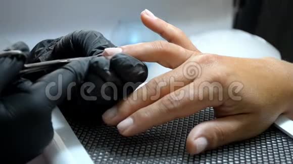 手套中的手感师用薄剪刀从客户手指上切割角质层视频的预览图