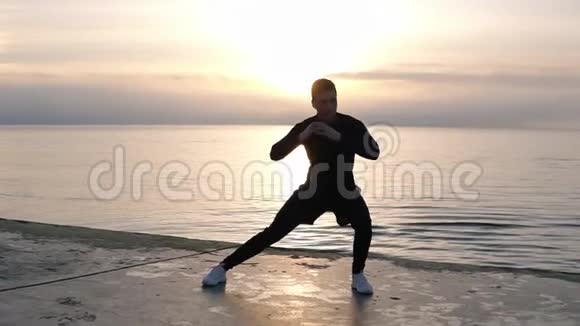肌肉发达穿短裤的高个子男人在靠近大海的木地板上热身锻炼腿部靠身体伸展视频的预览图