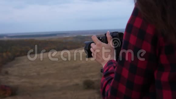 年轻独立女旅游摄影师用专业数码相机拍摄美丽的秋景视频的预览图