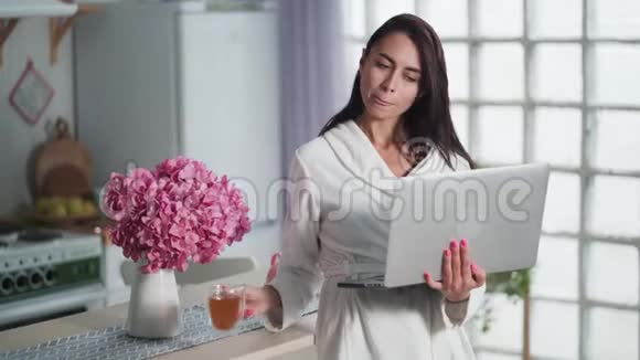 年轻女性自由职业者使用笔记本电脑在家工作早上喝茶视频的预览图
