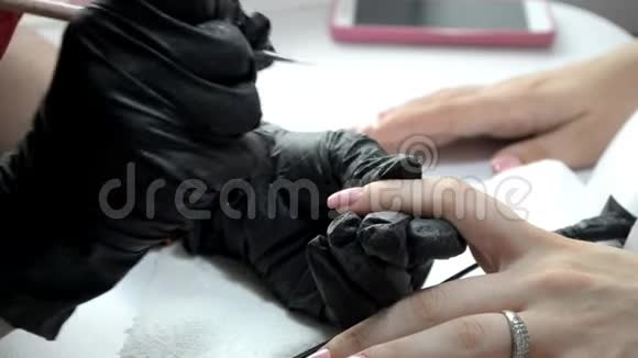 戴黑色手套的指甲油师傅在指甲上涂粉红色指甲油视频的预览图
