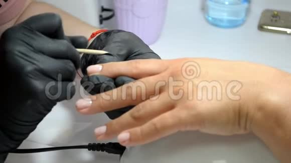 戴黑手套的修指甲师傅用竹木棍在指甲上工作视频的预览图