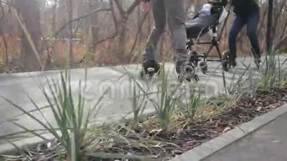 在温暖的秋日里年轻的运动父母和他们的孩子坐着婴儿车在小巷里滑旱冰爸爸骑车视频的预览图