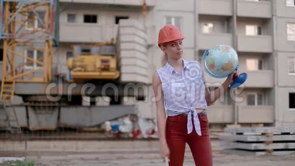 小巧可爱的年轻女子戴着建筑头盔手里拿着地球仪可调节的扳手指向乡村或城市视频的预览图