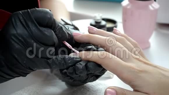 戴黑色手套的指甲油师傅在指甲上涂粉红色指甲油视频的预览图