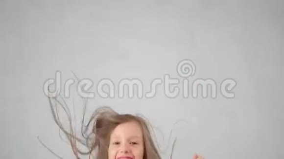 特写快乐可爱的小女孩跳起手在白色的工作室背景下享受快乐视频的预览图