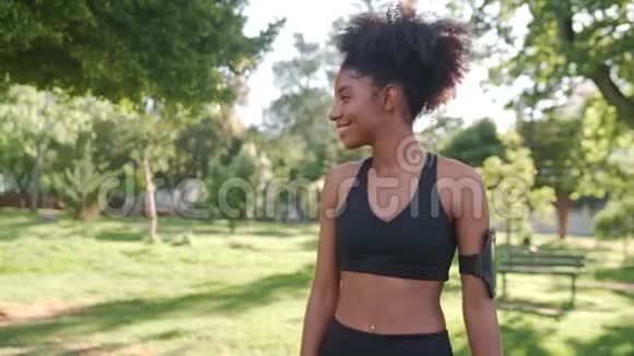 一位非洲裔美国年轻健康的女性拥抱着她的女性朋友在阳光明媚的日子里微笑着看着公园里的摄像机视频的预览图