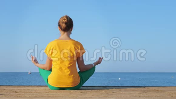 穿着五颜六色衣服的年轻女子在海边或海洋上练习瑜伽视频的预览图
