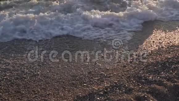 在鹅卵石滩日落日出时用白色泡沫关闭海浪的慢动作视频黑山亚得里亚海视频的预览图