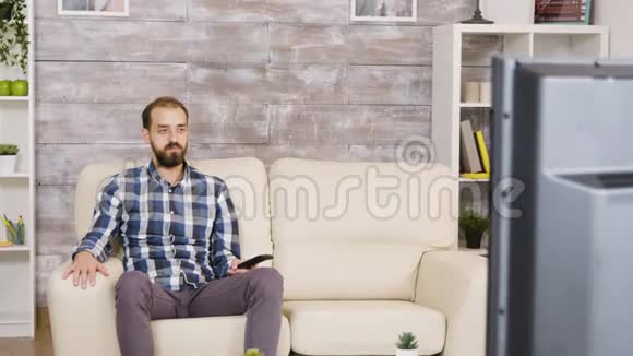 一个满脸严肃地坐着看电视的大胡子男人视频的预览图
