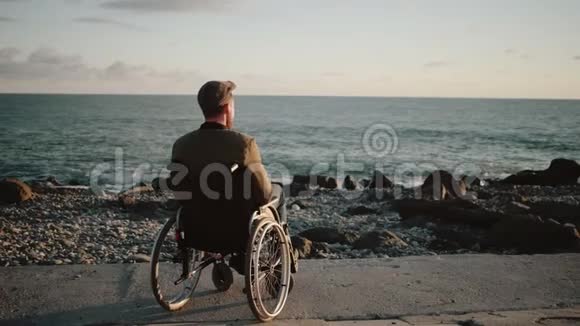男残疾人正在看海平面举起手向后看视频的预览图