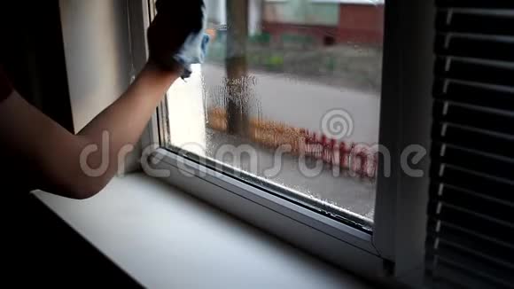 男人在家里洗窗户用洗水喷雾和除尘器清洗窗户视频的预览图