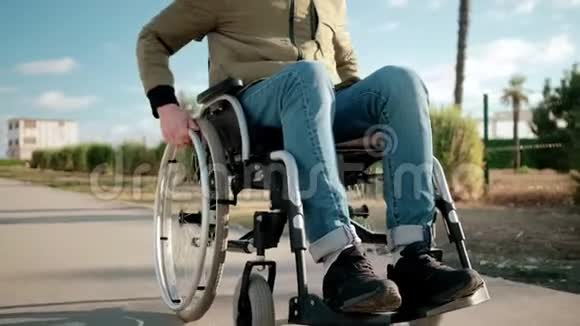 年轻的男性轮椅使用者正在城市街道上翻滚详细的腿部景观视频的预览图