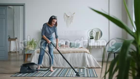 年轻的家庭主妇在卧室用吸尘器打扫地板独自工作视频的预览图