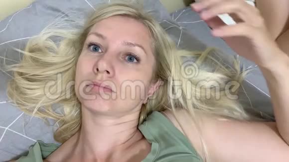 一位体贴而轻松的金发女人躺在床上抚摸着她的头发视频的预览图