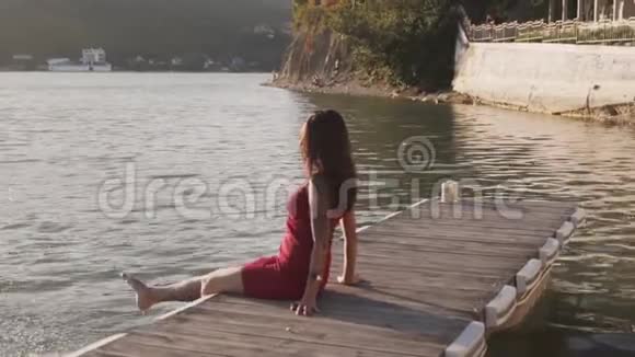 女人坐在木墩上双脚在湖水中飞溅动作缓慢视频的预览图