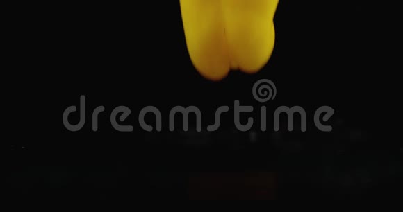 黄色多汁的切铃椒落在玻璃上水在黑暗的背景上缓慢地飞溅视频的预览图