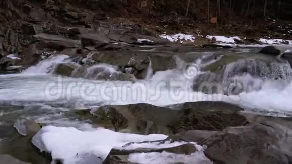 冬天的瀑布会腐烂从山溪里快速流出的水和带雪的石头急流视频的预览图