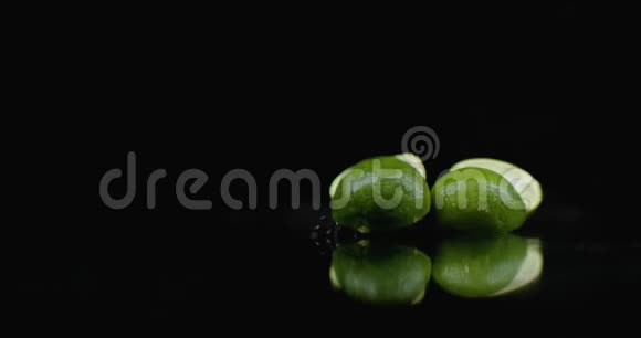 两只成熟的绿色石灰落在玻璃上在黑暗的背景上缓慢地溅起水花视频的预览图