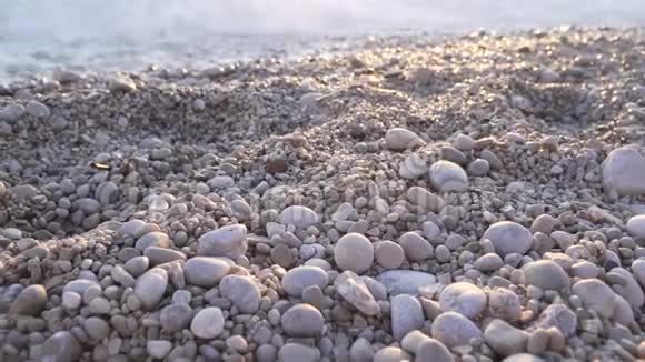 日落日出时海滩上的灰色卵石海岸海洋海岸波浪视频的预览图