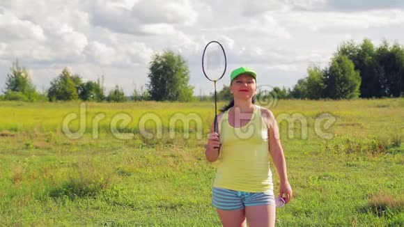 草地上的一个女人在打羽毛球时球视频的预览图
