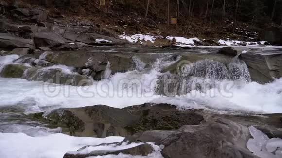 山溪和石头急流与雪水的快速流动冬季瀑布慢动作视频的预览图