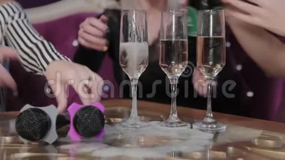 女孩用麦克风把香槟倒进桌子上的眼镜里视频的预览图