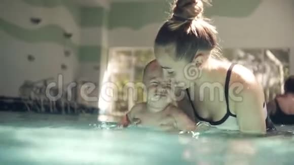 年轻的母亲穿着游泳衣带着她的小宝宝第一次潜入水中把他拉到水下视频的预览图