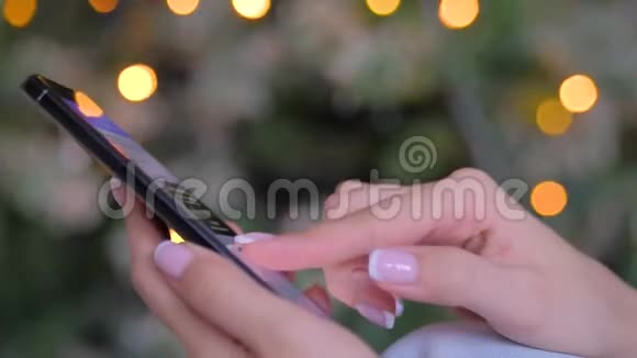 女士使用智能手机圣诞灯背景关闭视频的预览图
