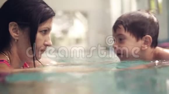 妈妈在室内游泳池里教儿子在水下游泳水下射击小男孩在水下划船视频的预览图