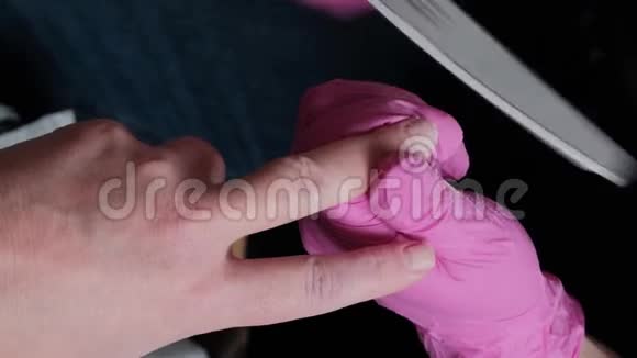 穿着粉红色手套的美甲师在美甲沙龙中用假指甲切割角质层和紫胶脚趾甲美容师的专业美甲视频的预览图