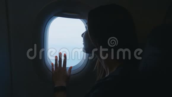 坐飞机旅行的女人年轻的女旅行者坐在座位上一边飞一边看着窗外的飞机视频的预览图