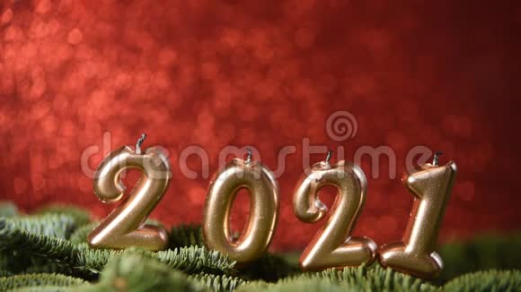 假日背景2021年新年快乐2021年的数字是由在红色的节日闪闪发光的背景上燃烧金蜡烛制成的视频的预览图