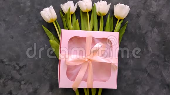 白色郁金香花与粉红色礼品盒在深灰色背景平躺4K视频视频的预览图