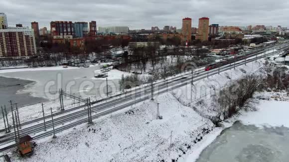 航景飞行跟踪一列移动轨道列车在结冰的河流上行驶的桥梁视频的预览图
