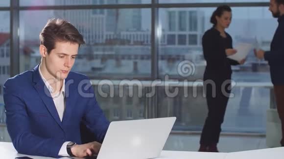 英俊的商人在办公室工作专注的年轻人在笔记本电脑上打字视频的预览图