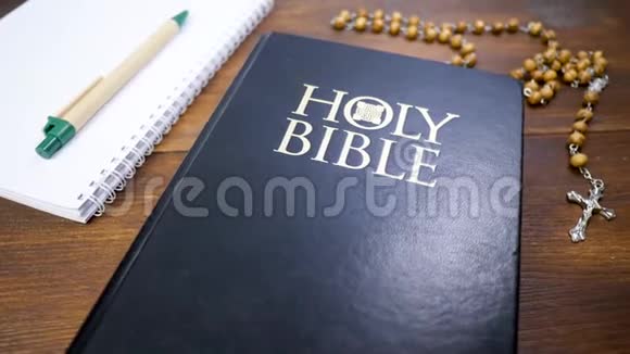 神圣的圣经在棕色木桌背景上有十字架的珠子视频的预览图